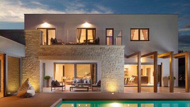 Uma casa moderna de dois andares com piscina, área de estar externa e fachada de pedra.