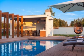 A pool area with a pergola, seating, and a hanging chair. - Villa Royal Green (Rasa)