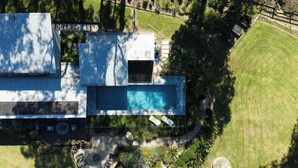 An aerial view of a modern house with a swimming pool, a deck, and a well-maintained lawn. - The Pavilion, Wamberal (Wamberal)