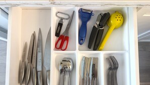 A drawer with various kitchen utensils organized in compartments.