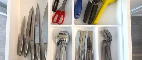 Un tiroir contenant divers ustensiles de cuisine, rangés dans des compartiments.