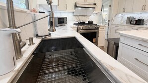 A modern kitchen with a stainless steel sink, a built-in oven, and a microwave.