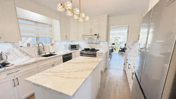 A modern kitchen with a marble countertop, stainless steel appliances, and a central island. - Vancouver Lucy House (Vancouver)