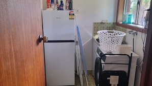 Une cuisine compacte équipée d’un réfrigérateur, d’un lave-linge et d’une fenêtre donnant sur un paysage agréable.