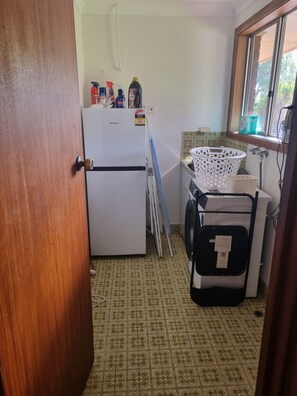 A compact kitchen with a refrigerator, a washing machine, and a window with a view. - Barnard Beach House
Family home welcoming dogs. Walking distance to the beach. (Broadwater)