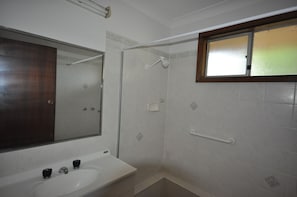 A bathroom with a white sink, a mirror, a shower with a glass door, and a window with frosted glass. - Barnard Beach House
Family home welcoming dogs. Walking distance to the beach. (Broadwater)