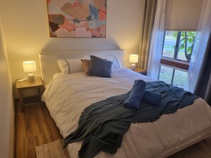 A hotel room with a bed, two bedside lamps, a nightstand, a window with curtains, and a painting on the wall. - Barnard Beach House
Family home welcoming dogs. Walking distance to the beach. (Broadwater)