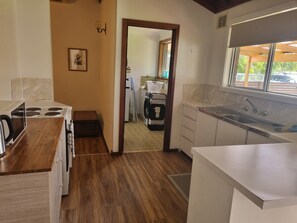 A kitchen with a stove, sink, and wooden flooring. - Barnard Beach House
Family home welcoming dogs. Walking distance to the beach. (Broadwater)