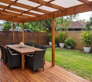 A covered patio with a wooden table and chairs, surrounded by potted plants. - Barnard Beach House
Family home welcoming dogs. Walking distance to the beach. (Broadwater)