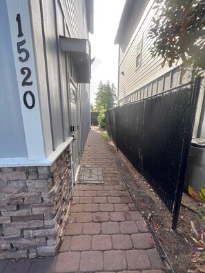 A narrow brick pathway leading to a building with a number '1520' on the wall.