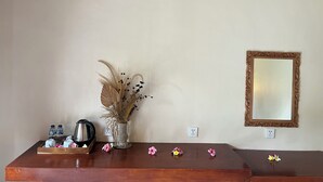 Una mesa de madera con un florero de plantas secas, una bandeja con botellas y un espejo en la pared.