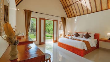 A bedroom with a large bed, a wooden desk, and a view of the outdoors.
