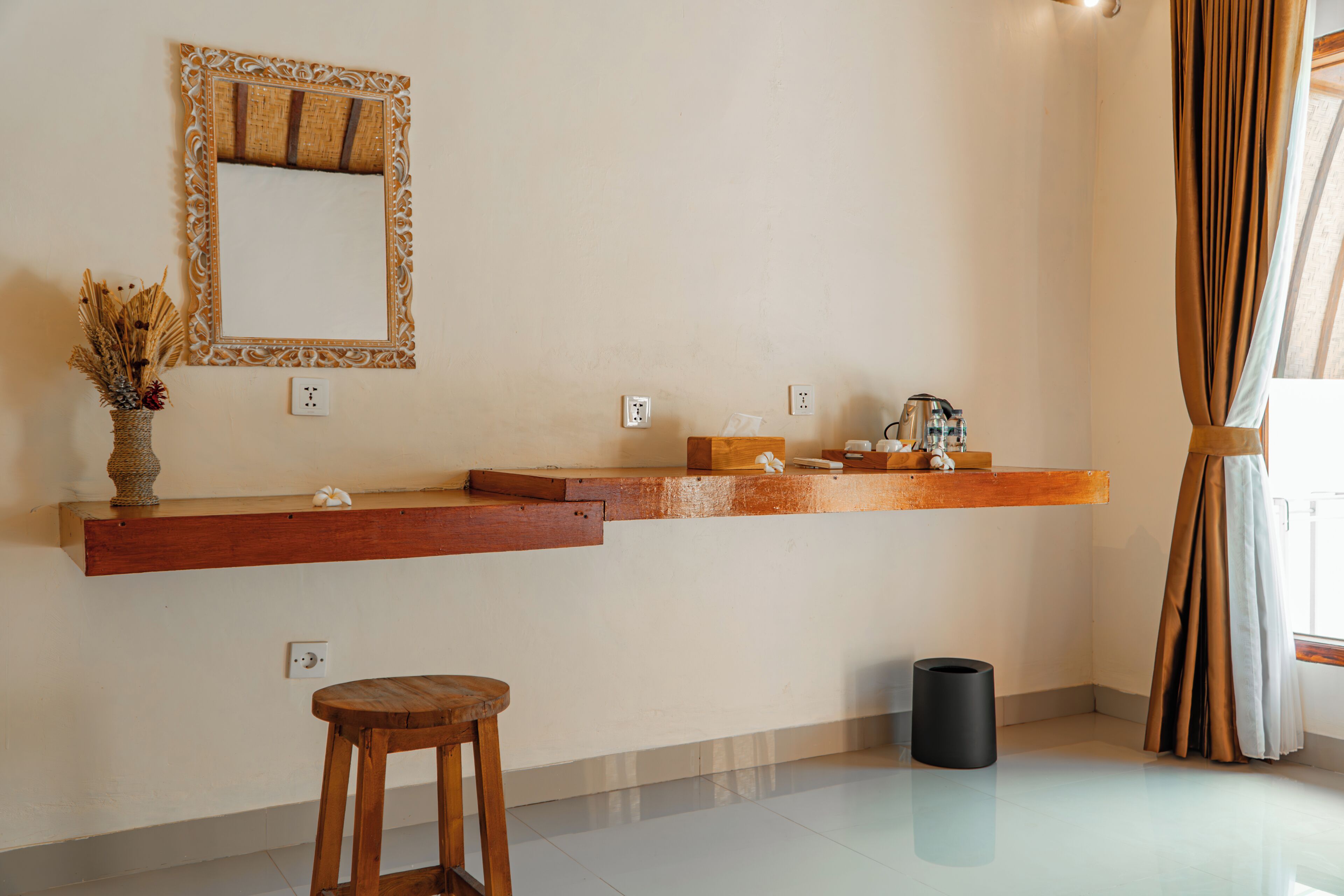 A bathroom with a wooden vanity, a mirror with an ornate frame, and a small stool.