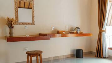 A bathroom with a wooden vanity, a mirror with an ornate frame, and a small stool.