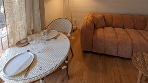 Uma sala de estar aconchegante com uma mesa redonda posta para refeições, um sofá e um abajur.