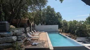 Piscina com espreguiçadeiras e um muro de pedra.
