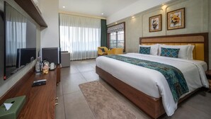 A modern hotel room with a large bed, a flat-screen TV, a ceiling fan, and a desk with a chair.