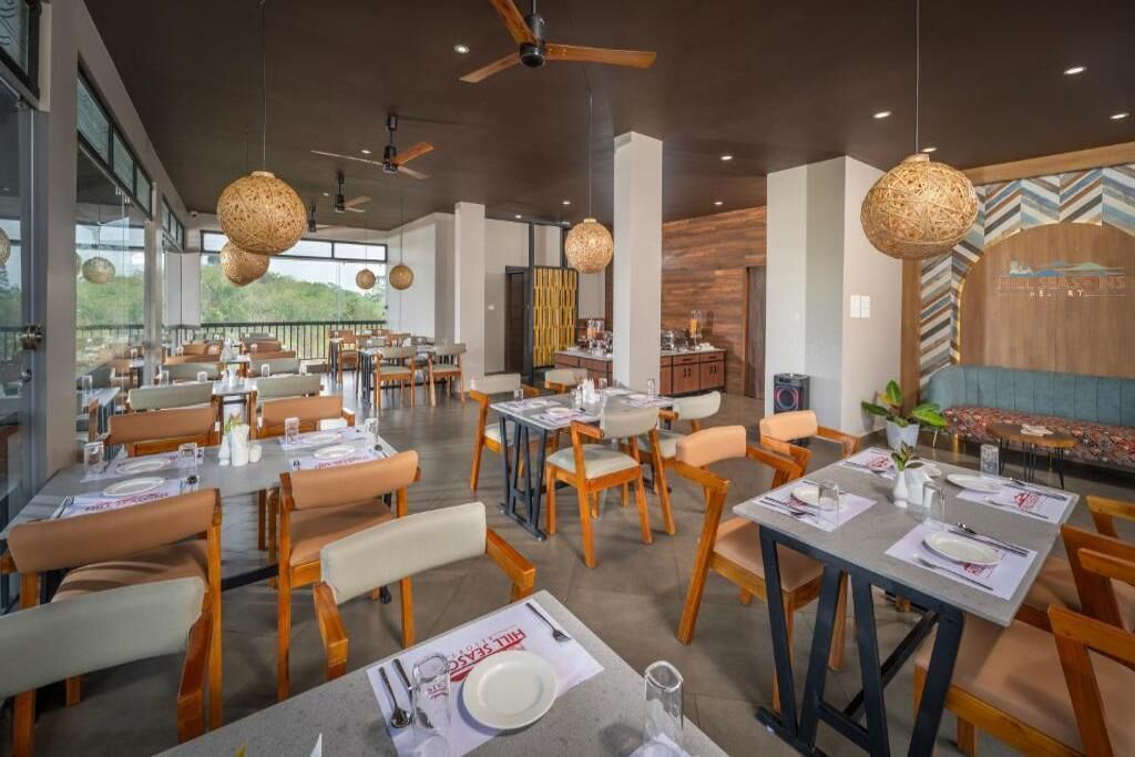 Ein Restaurant mit mehreren Tischen, Stühlen und hängenden Leuchten.