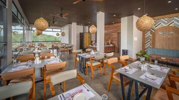 Ein Restaurant mit mehreren Tischen, Stühlen und hängenden Leuchten.
