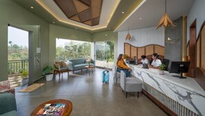 A modern hotel lobby with a reception desk, seating area, and large windows offering a view of the outdoors.