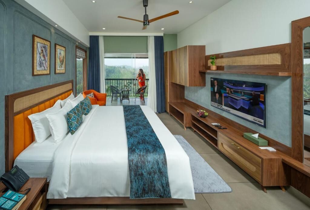A hotel room with a large bed, a television, a balcony, and a view of the outdoors.