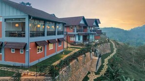 A multi-story hotel with balconies, a stone retaining wall, and a pathway leading uphill.
