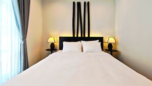 A hotel room with a large bed, two bedside tables with lamps, a modern headboard, and a view of the outdoors through the window. - JMO Boutique Hotel & Spa Phu Quoc (Phu Quoc)
