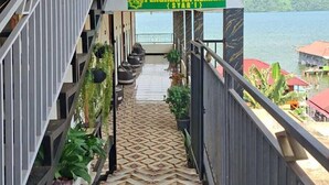 A staircase leading to a covered area with a view of the sea, a sign reading 'PENGINAPAN REMAJA (SVAR I)', and a tiled floor. - Penginapan Remaja Morowali (Kolonodale)