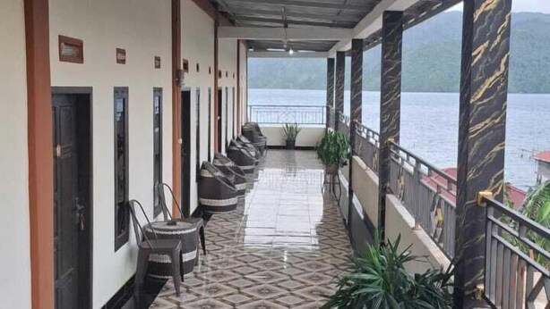 A corridor with a tiled floor, chairs, and a view of a body of water. - Penginapan Remaja Morowali (Kolonodale)