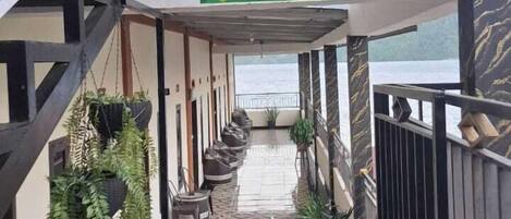 A corridor with a tiled floor, potted plants, and a sign reading 'PENGINAPAN REMAJA SYAIRI'.