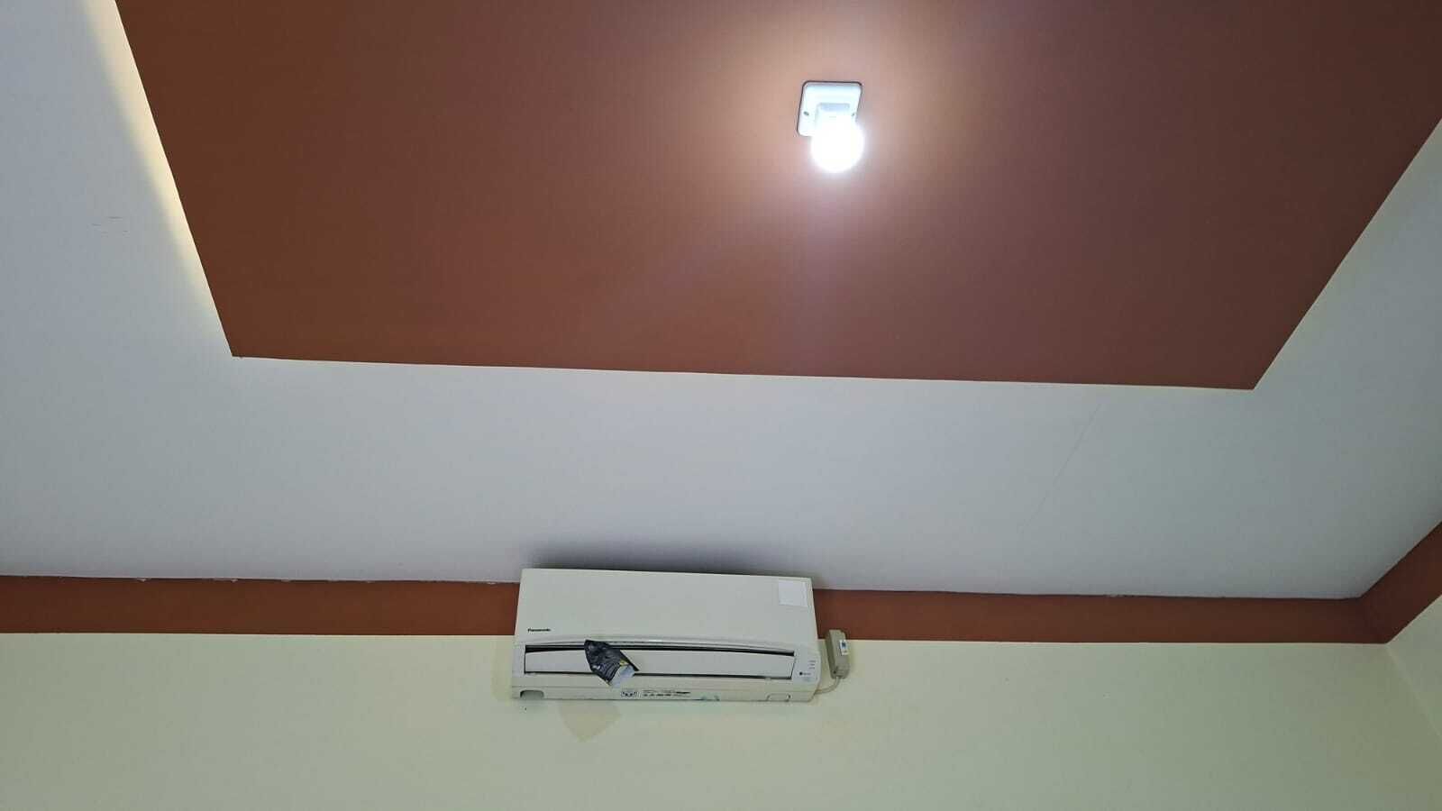 Eine Decke mit einer eingelassenen Leuchte und einer an der Wand befestigten Klimaanlage.
