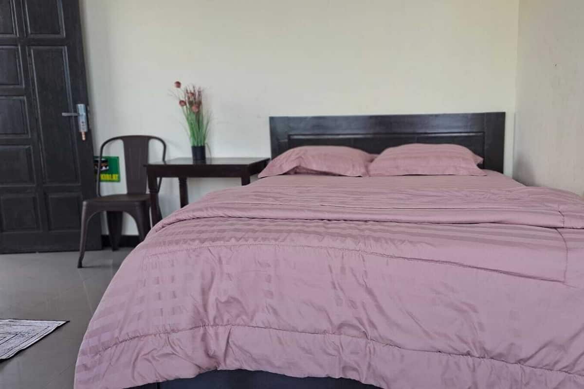Een slaapkamer met een bed, een nachtkastje, een stoel en een deur.