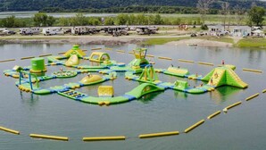 Parque acuático con estructuras inflables y un lago.