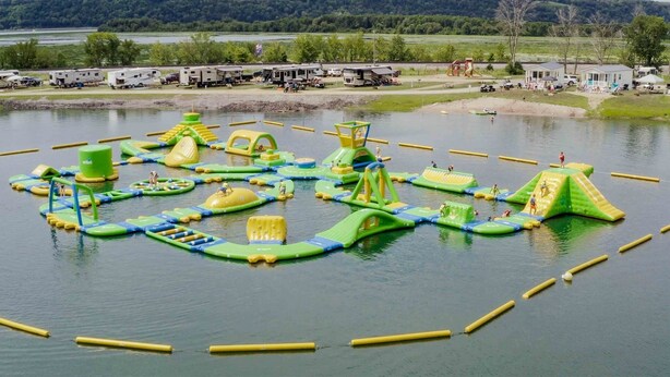 Een waterpark met opblaasbare speelconstructies en een meer.