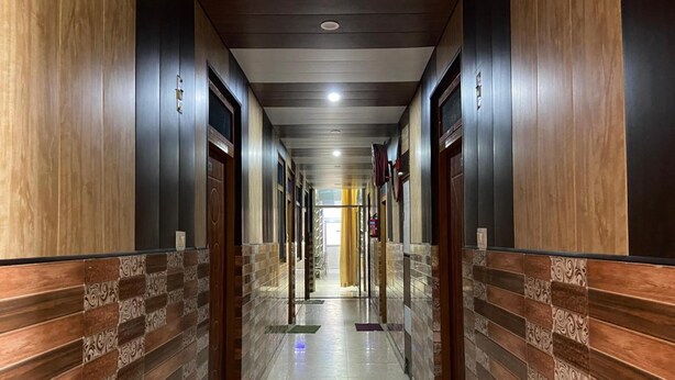 A hallway with wooden paneling, doors, and a tiled floor. - Raj Palace (Joshimath)