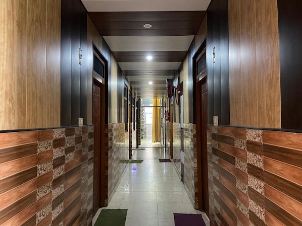 Um corredor com painéis de madeira, portas e piso ladrilhado.