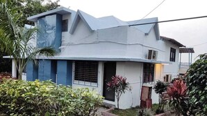 A modern two-story house with a flat roof, a small porch, and a garden with various plants. - Shagun Resort & Water Park (Igatpuri)