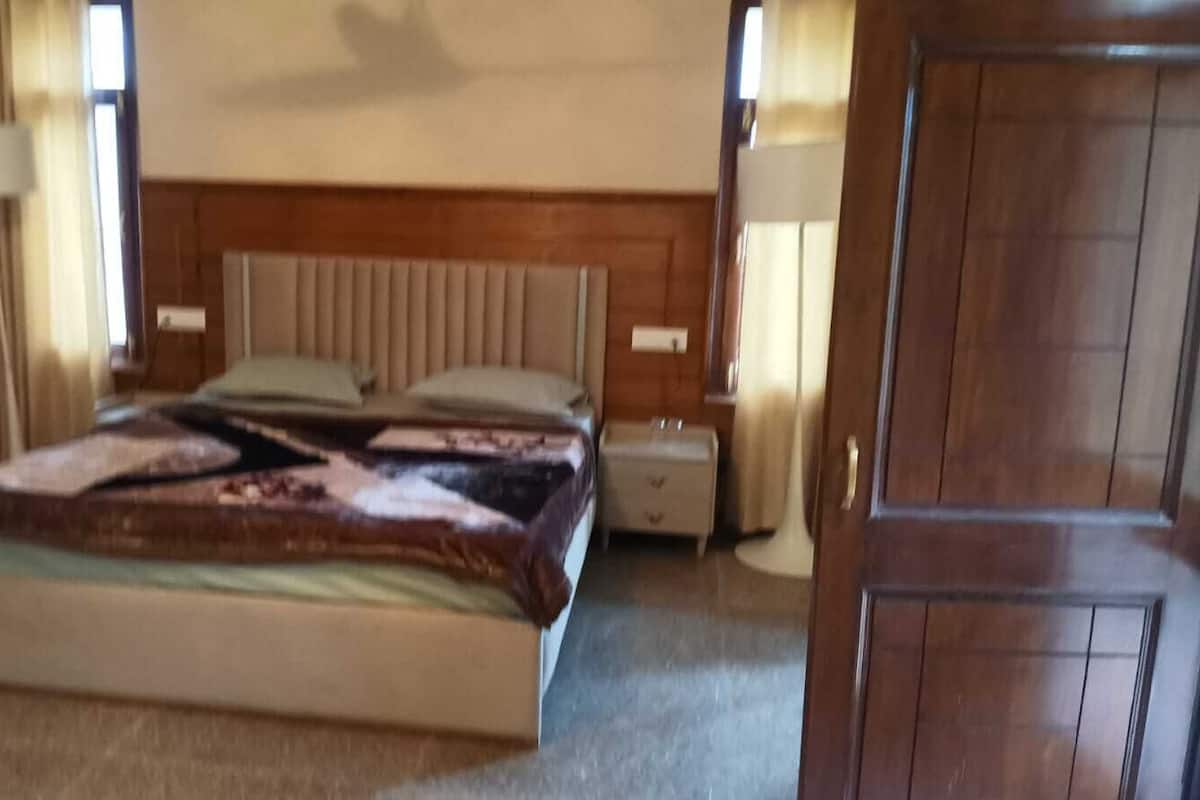 Un dormitorio con cama, mesitas de noche, un tocador y un armario.