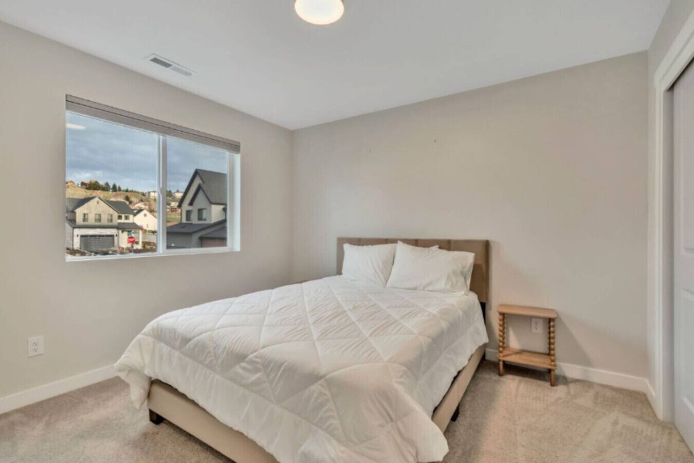 Un dormitorio con cama, una ventana con vistas y una mesita de noche.
