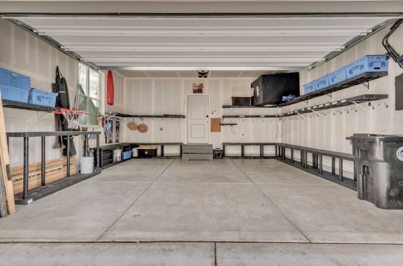 A spacious indoor area with a concrete floor, metal railings, and storage shelves.