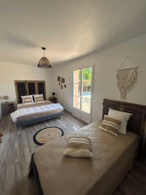Une chambre à coucher avec un lit, un luminaire suspendu, une porte donnant sur l’extérieur et des éléments décoratifs sur les murs.