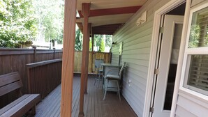 Une terrasse couverte avec un banc, une table et des chaises, ainsi qu’une porte dotée d’une fenêtre.