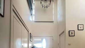A hallway with a chandelier, white doors, and a staircase. - House is near to university, AIS, mountain, lake and CBD. Family - friendly. (Bruce)