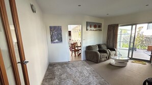 A spacious living room with a large rug, a sofa, and a dining area in the background. - House is near to university, AIS, mountain, lake and CBD. Family - friendly. (Bruce)