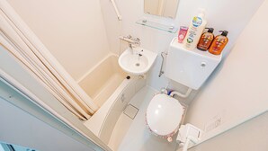 Et badeværelse med badekar, vask, toilet og hylder med toiletartikler.