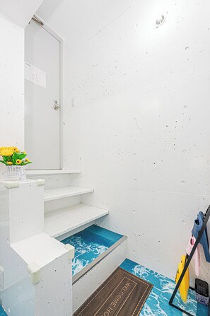 Un baño con lavamanos blanco, un espejo, un ventanal pequeño y una zona de ducha con azulejos azules.