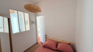 A bedroom with a bed, a woven light fixture, a door, and a window. - Charming, cosy apartment in the Antique Quarter (Marseille)