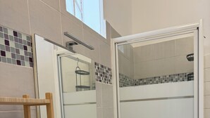 A bathroom with a white sink, a mirror, a wooden shelf, and a shower area. - Charming, cosy apartment in the Antique Quarter (Marseille)