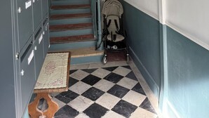 A narrow hallway with a checkered floor, a staircase, and a baby stroller. - Charming, cosy apartment in the Antique Quarter (Marseille)