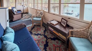 Una habitación acogedora con un ventanal grande, muebles de mimbre y una alfombra.